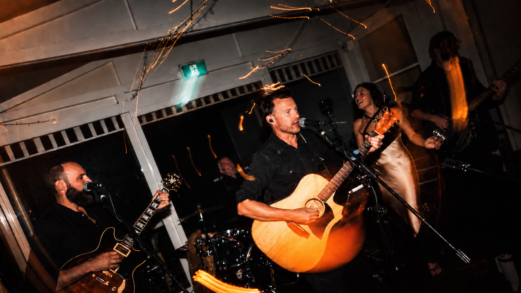 Still Slaps performing live — lead singer with acoustic guitar and bandmates on stage
